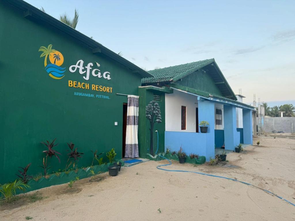 a green building with a beach resort sign on it at Afaa Beach Guest House in Arugam Bay