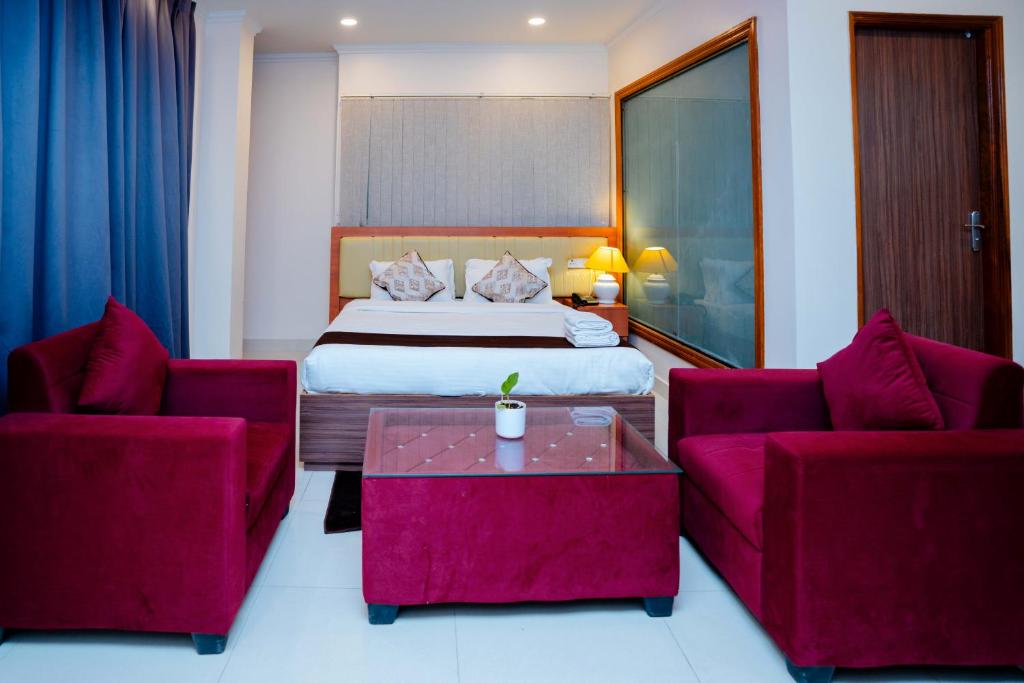 a hotel room with a bed and two red chairs at Hotel octavia in Imphal