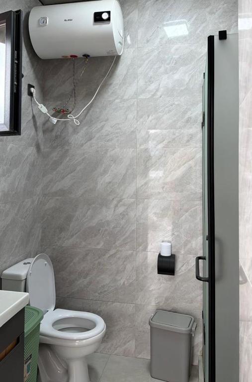 a bathroom with a white toilet and a shower at Alpha White in Koshkolʼ
