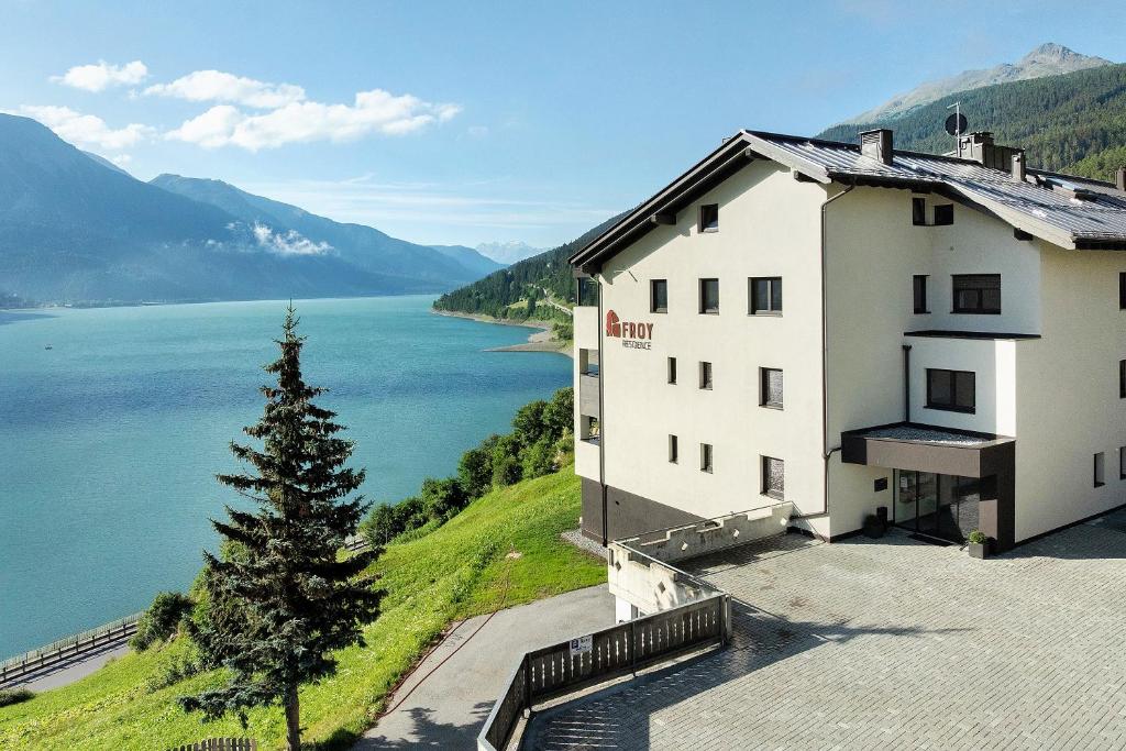 a building on a hill next to a body of water at Residence Froy in Resia