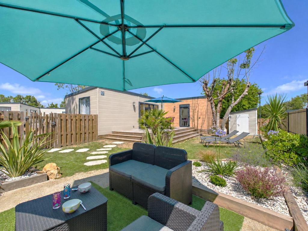 a patio with a blue umbrella in a yard at Piscine chauffée commune, 2 adultes 2 enfants in Saint-Gilles-Croix-de-Vie