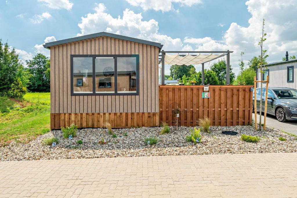 a tiny house with a fence and a car at Zwerg Nase in Dörverden
