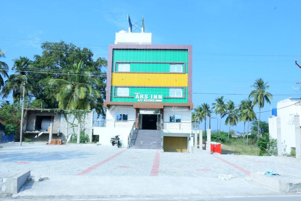 a building with a yellow and green sign on it at ars inn and mini hall in Tiruvallam