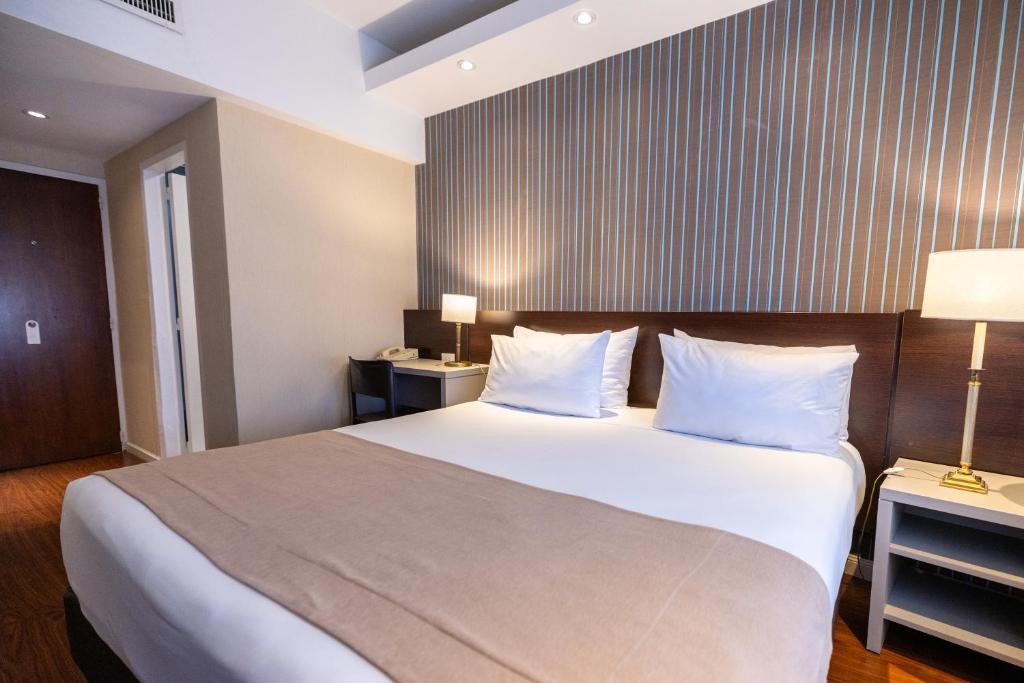 a hotel room with a large bed with white pillows at Dorá Hotel Buenos Aires in Buenos Aires
