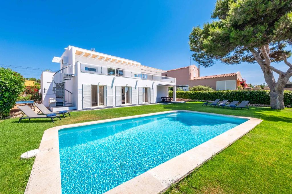 a villa with a swimming pool in front of a house at Villa Sol de Flandes in Punta Prima