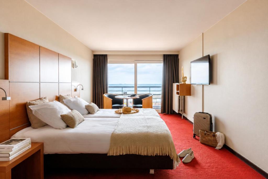 a hotel room with a large bed and a desk at Hotel Riant-Séjour Seaview by WP Hotels in Blankenberge