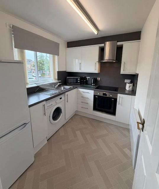 a kitchen with white cabinets and a dishwasher at Kelpies Serviced Apartments Alexander- 2 Bedrooms in Falkirk