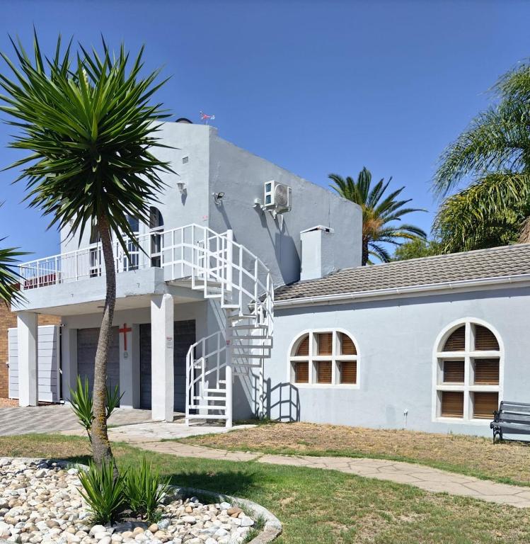 a white house with a palm tree in front of it at The Room Above in Brackenfell