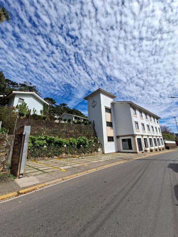 a white building on the side of a street at Pousada Il Villaggio in Santo Antônio do Pinhal
