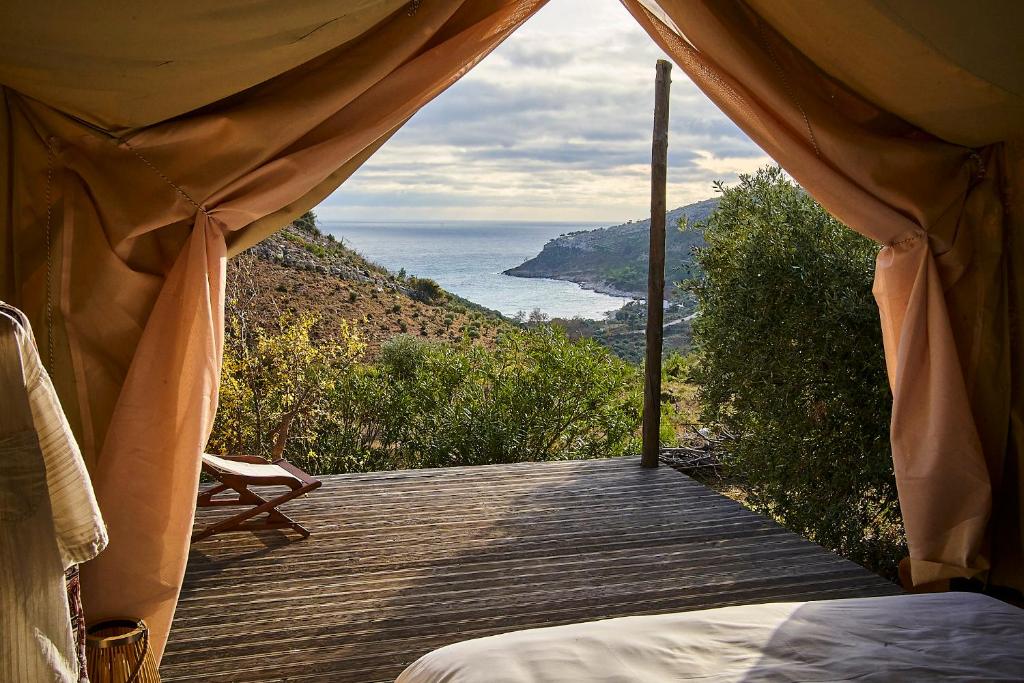 a bed on a wooden deck with a view of the ocean at Billion Stars in Thymonia Beach