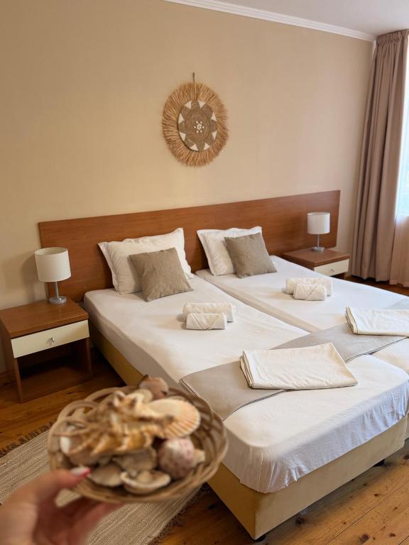 two beds in a hotel room with a person holding a plate at Къща за гости Смокиня in Obzor