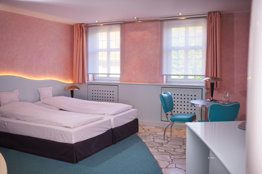 a bedroom with a bed and a desk and windows at Hotel Goldener Karpfen OHG in Fulda