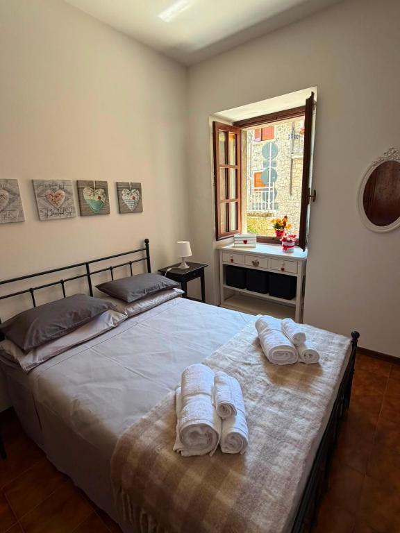 a bedroom with a bed with towels and a window at Cottage di Lola in Fonteno