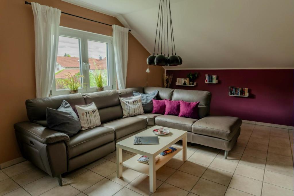 a living room with a leather couch and a table at Ferienwohnung Blumäcker Oberbayern in Oberhausen