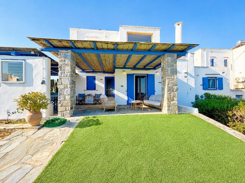 a patio with a green lawn in front of a house at villa kite paros in Pounda