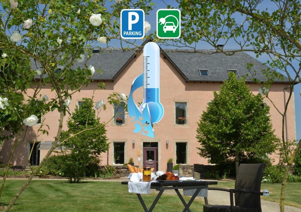 ein Haus mit einem Tisch davor in der Unterkunft HÔTEL LA FERME DE BOURRAN - RODEZ - parking privé avec bornes pour voitures électriques in Rodez