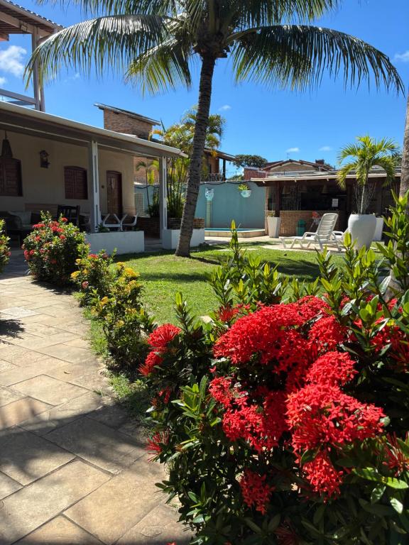 a garden with red flowers and a palm tree at Pousada Sapê in Praia do Frances