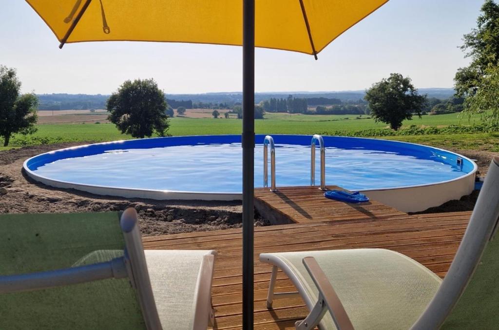 a swimming pool with an umbrella and chairs on a deck at Monet in Douzains