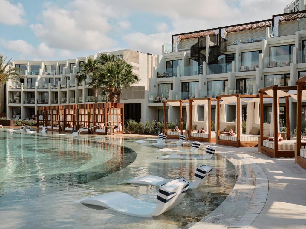 a hotel swimming pool with chairs in front of a building at BLESS Ibiza The Site - New Opening 2026 in Playa d'en Bossa