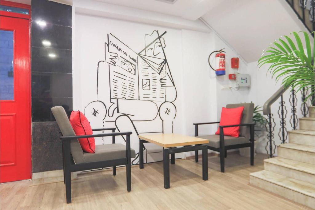 a waiting room with chairs and a table and a red door at Townhouse Royal Inn in Guwahati