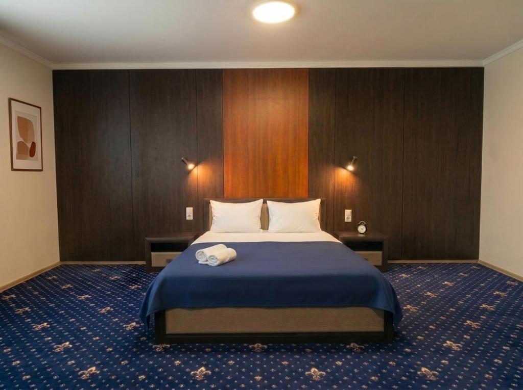 a bedroom with a large bed with a blue blanket at Oasis Hostel in Kostanay