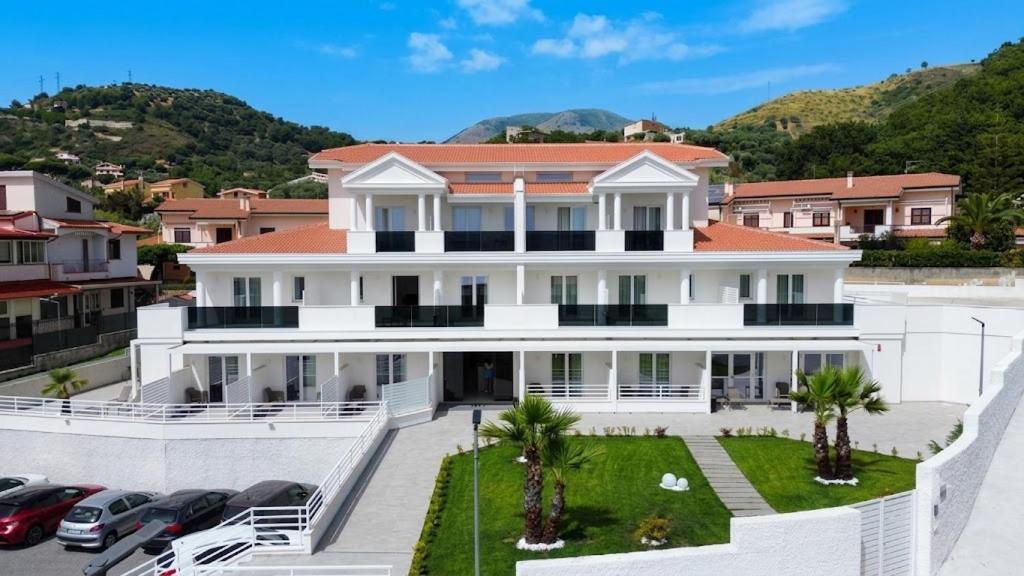 a large white house with cars parked in a parking lot at Hotel Diadema in Diamante