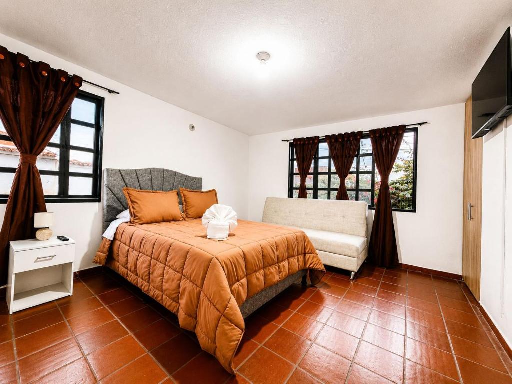 a bedroom with a bed and a chair and windows at hotel spa 360 villa de leyva in Villa de Leyva