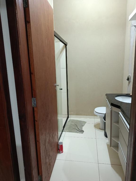 a bathroom with a toilet and a glass door at Pedacinho do céu 3 in Dourados