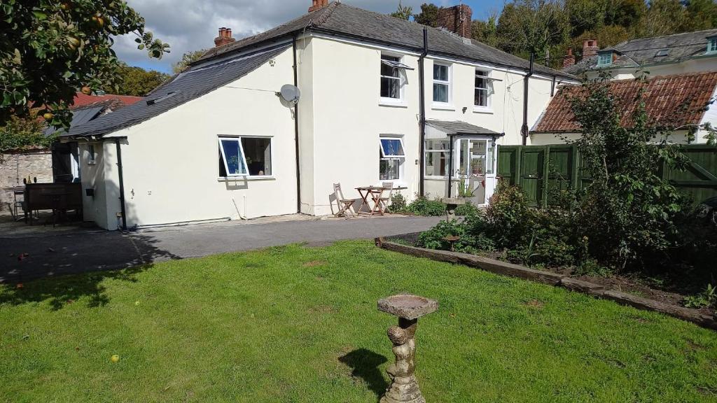 a white house with a bird bath in the yard at The Post Office, 6 beds, Bar, Library, Pool Table, Stream, Large Garden in Piddletrenthide