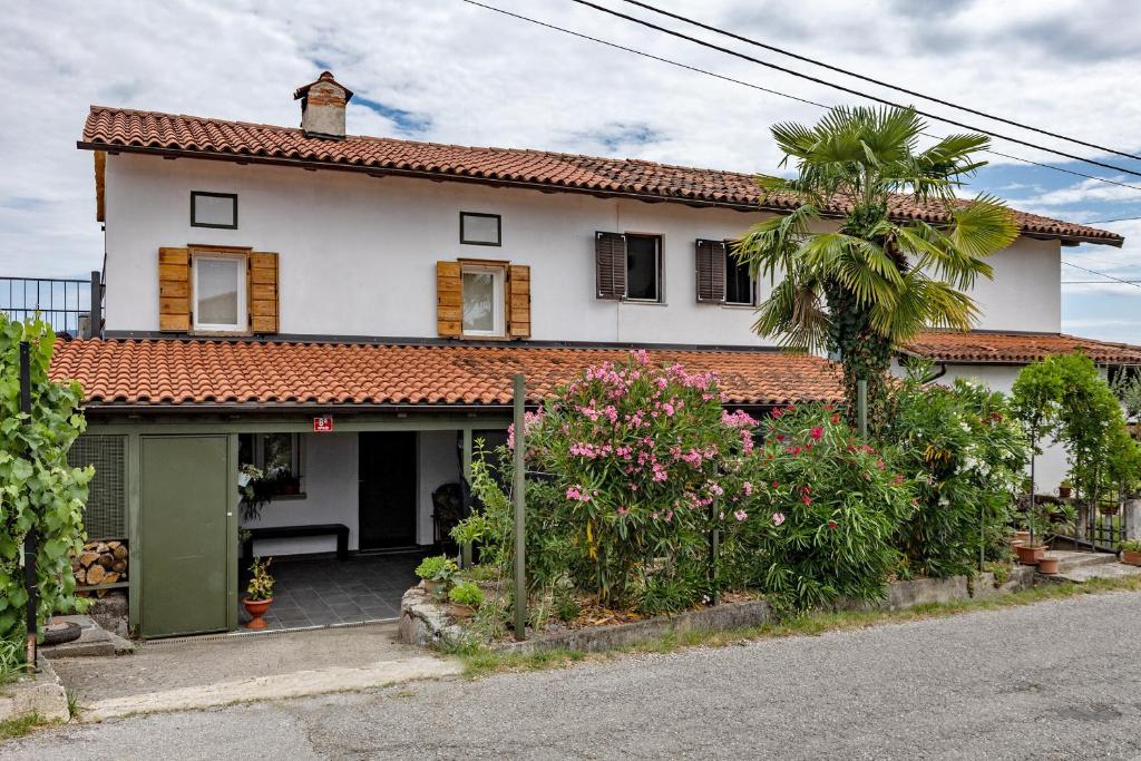 a white house with a palm tree in front of it at APARTMA BrdonKA in Dobrovo