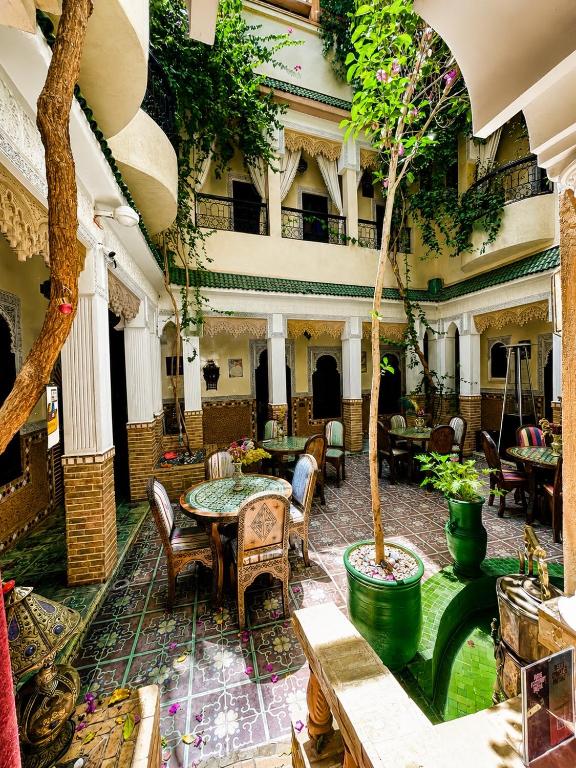 a courtyard with a table and chairs and a tree at Riad Olivier Marrakech medina in Marrakesh