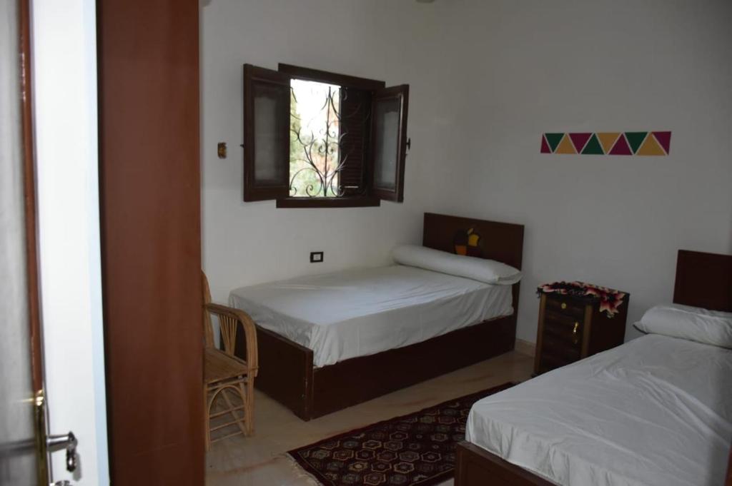 a small room with two beds and a window at Nobal best house in Aswan