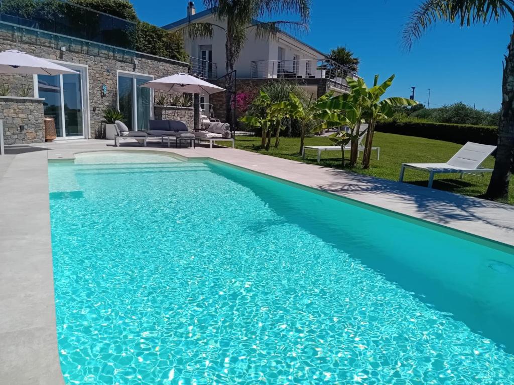 a swimming pool with blue water in front of a house at Vista Resort OPENING 13-7-26 in Albisola Superiore