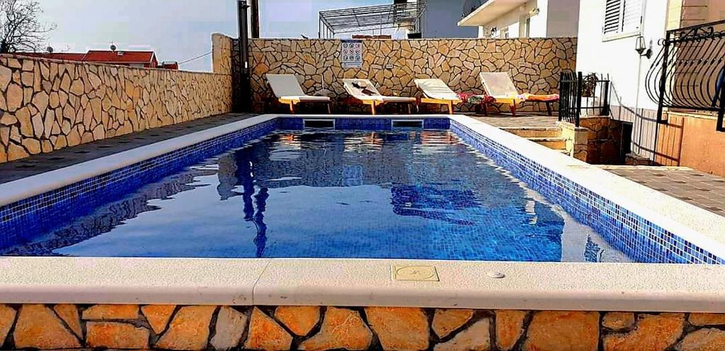 a swimming pool with two chairs and a swimming pool at Apartments Slavica Trogir in Trogir