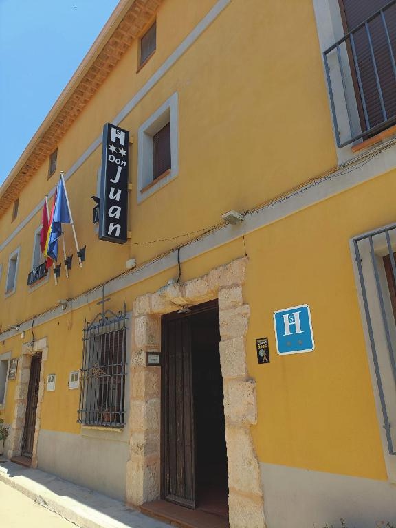 a yellow building with a door and a sign at Hostal Don Juan in Alarcón