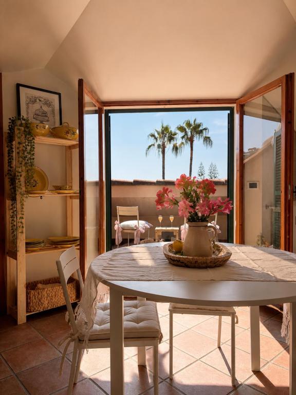 a dining room with a table with flowers on it at Maison Blanche in Bordighera