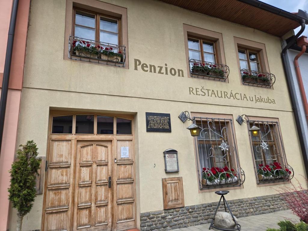a building with a door and windows and flowers at Penzión U Jakuba in Kežmarok