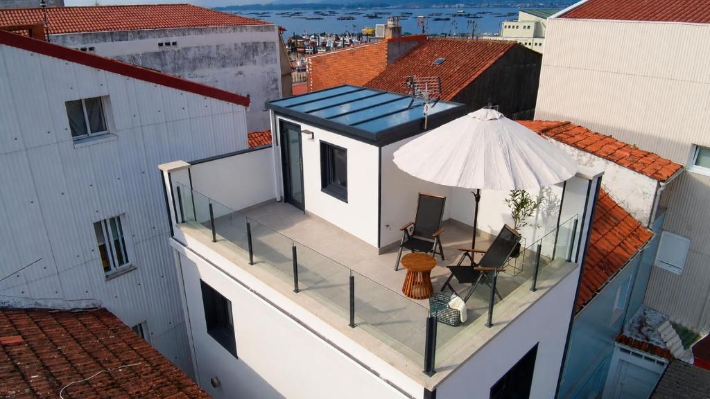 a balcony with a table and an umbrella on a building at Casa PedraMar in O Grove