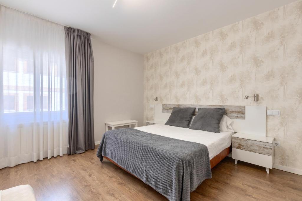 a bedroom with a white bed and a large window at Hotel Vivar in Griñón