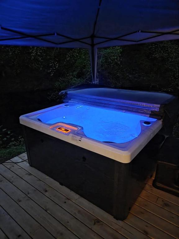 a hot tub sitting on a deck with an umbrella at Waters Edge Lodge in Caeathro