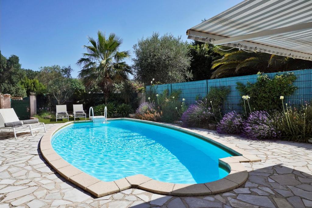 a swimming pool in a garden with a patio furniture and an umbrella at Ferienhaus Rafalenadjan, ideal für Familien, eigener Pool, schöne Terrasse, eigener Parkplatz by Riviera Homelife Management in Saint-Raphaël