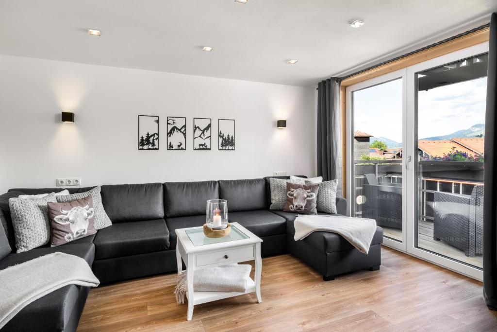 a living room with a black couch and a table at Landhaus Speiser in Bolsterlang