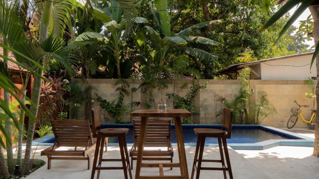 a table and chairs next to a swimming pool at Mango Garden in Gili Islands
