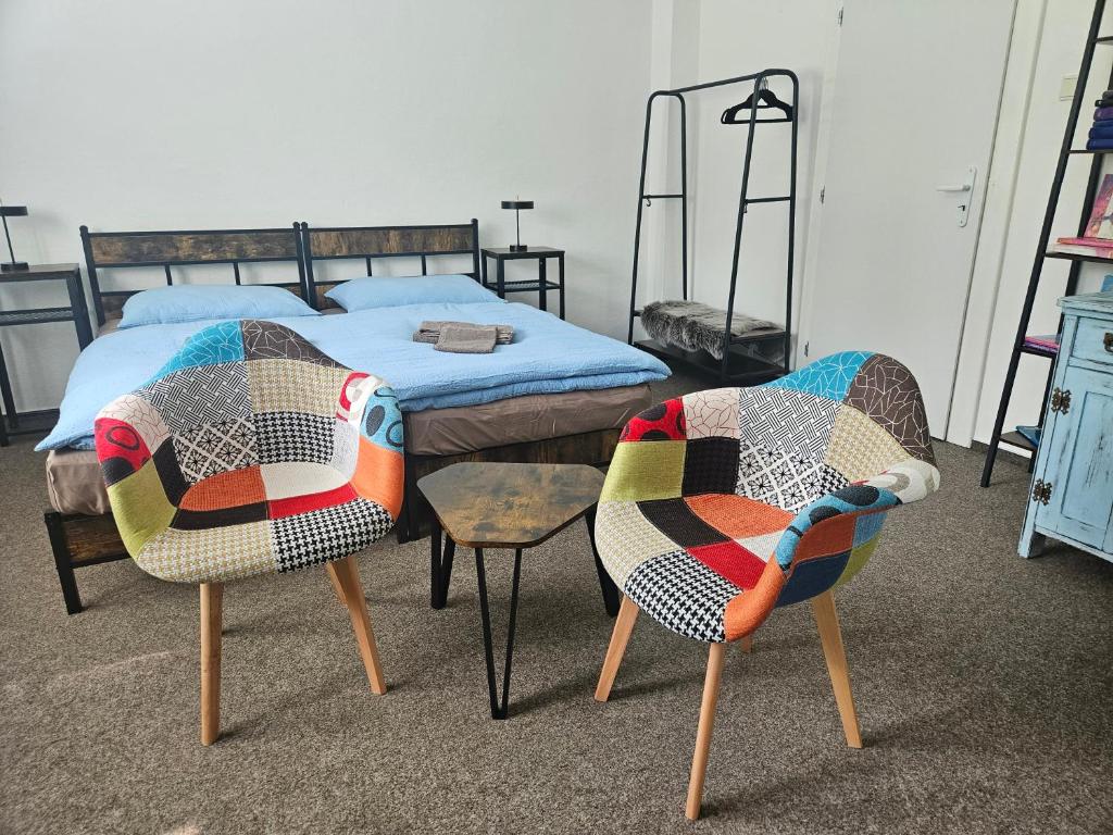 a bedroom with a bed and two chairs and a table at Privát ANAMON Gaštanová in Kežmarok