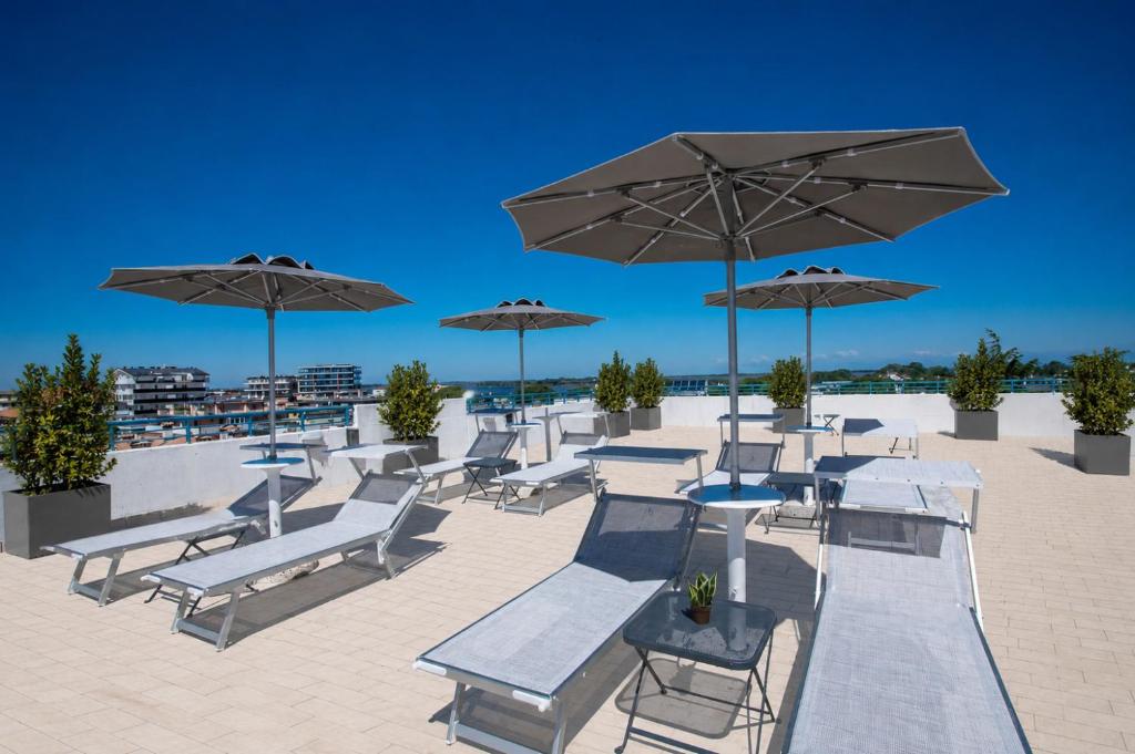 a group of chairs and umbrellas on a beach at Hotel Rialto in Grado