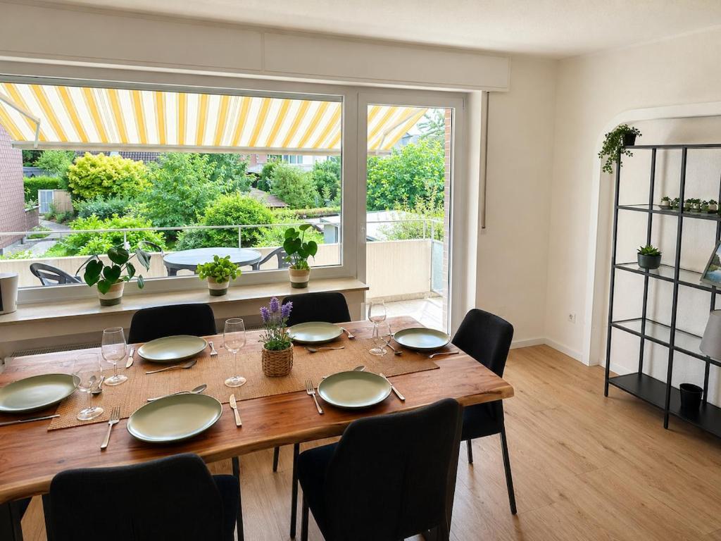 a dining room table with chairs and a large window at Green View - JK Apartments in Datteln