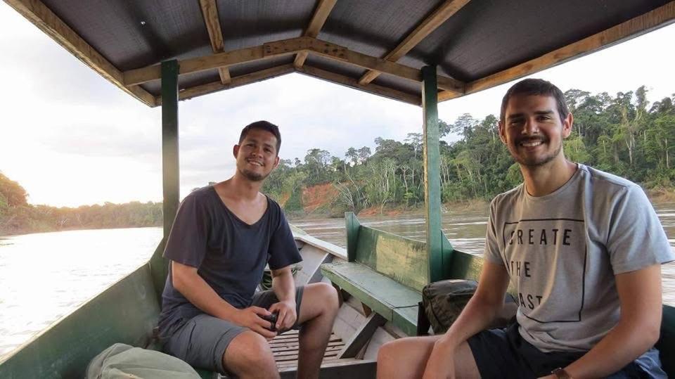 two men sitting in a boat on the water at Oropendola Expeditions in Tambopata