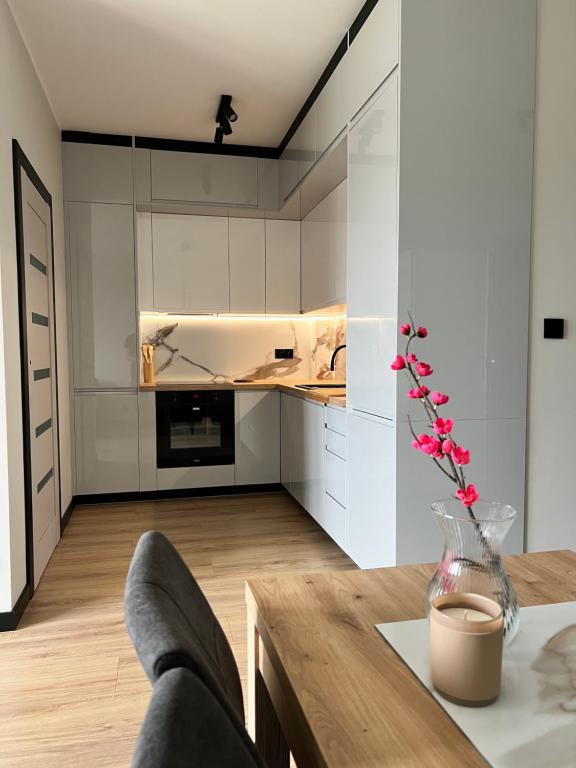 a kitchen with white cabinets and a wooden table at Apartament w Kębłowie in Kębłowo