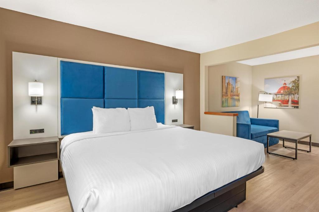a bedroom with a large bed with a blue headboard at Best Western Forsyth-Decatur in Forsyth
