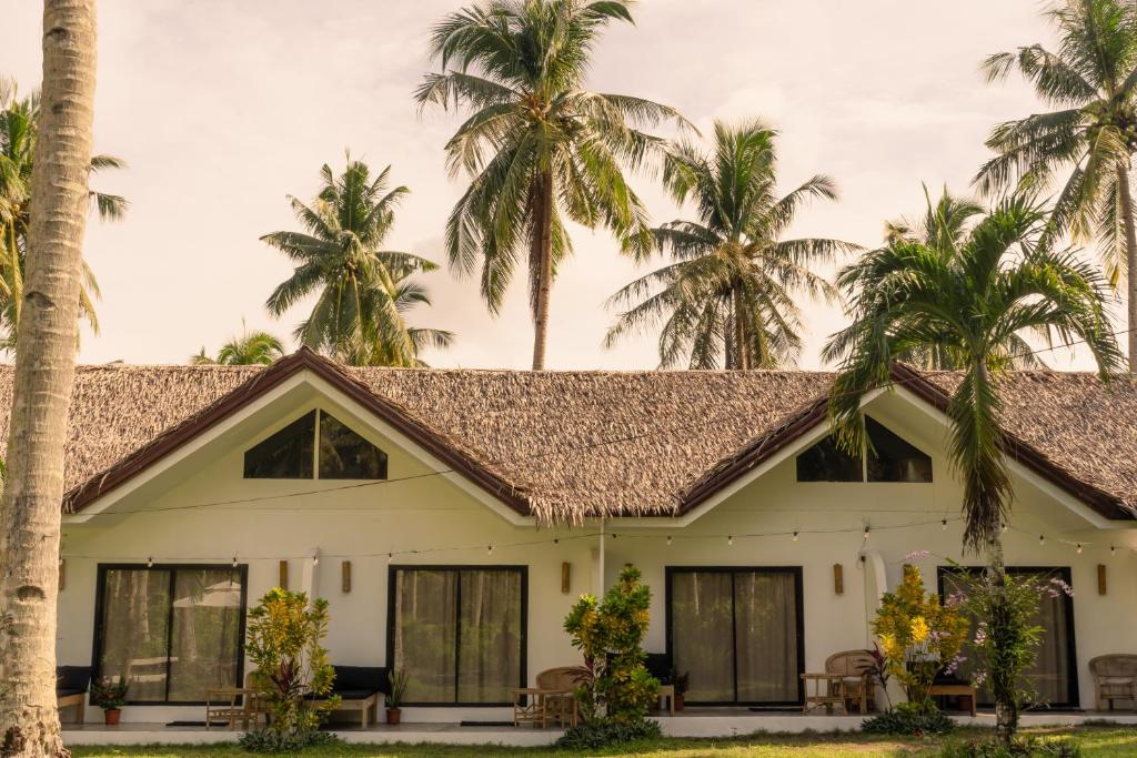 a house with palm trees in the background at Rodeo Sun Hotel in General Luna